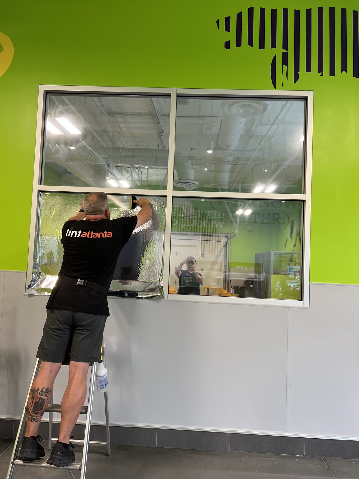 Tint Atlanta installer applying Opti 5 film to the PetSuites lobby viewing window